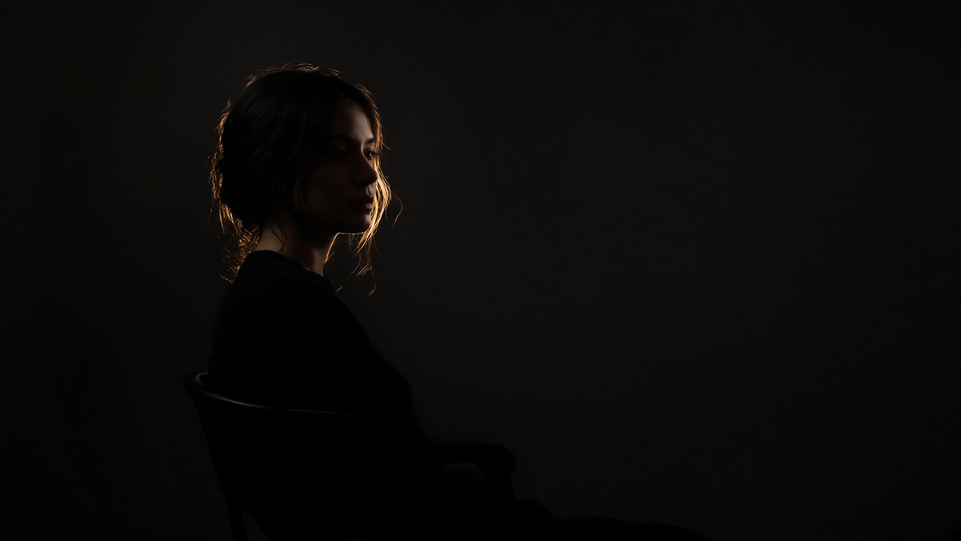 Low-key portrait sitting in a dark studio